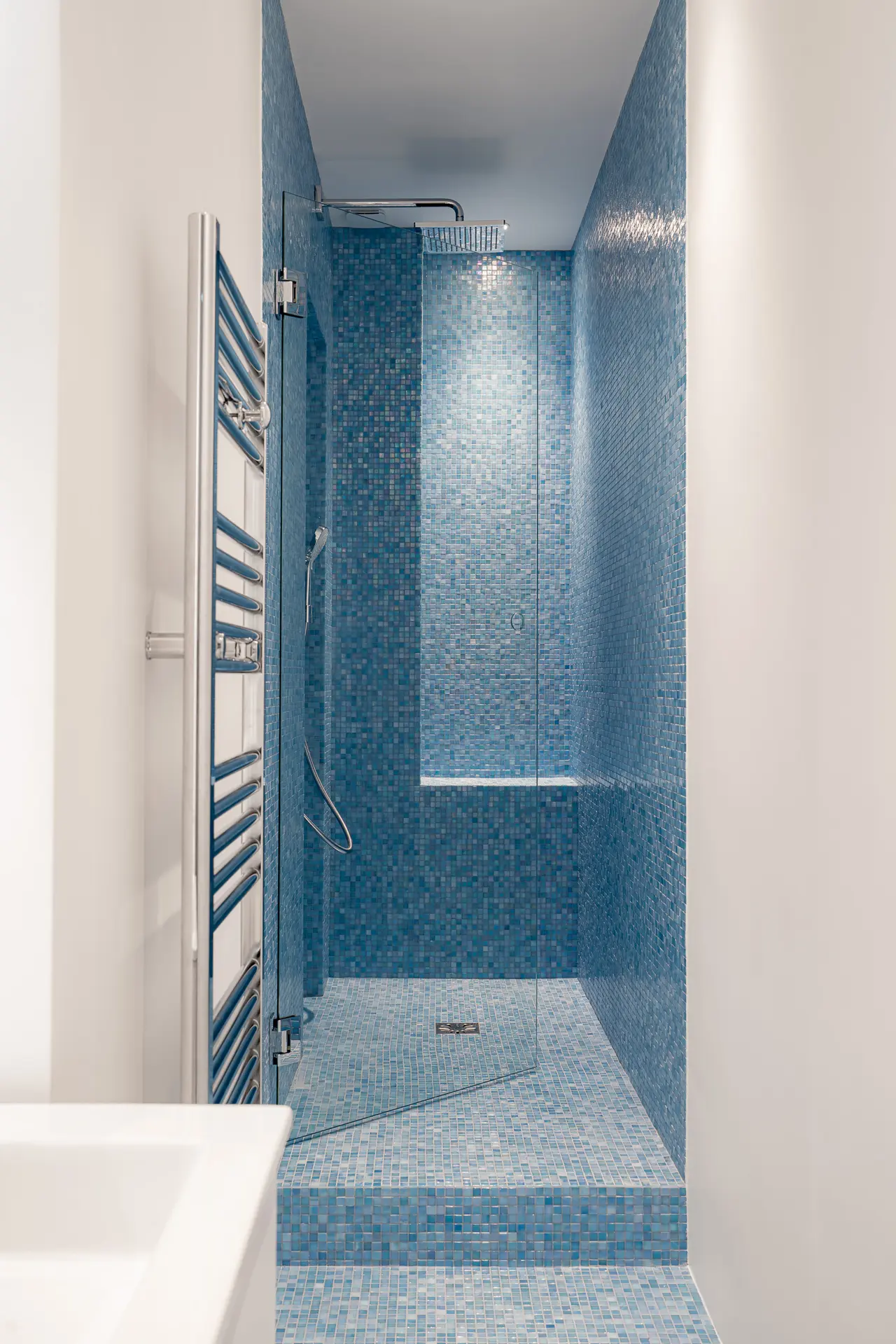 Vasque blanche et douche en mosaïque.