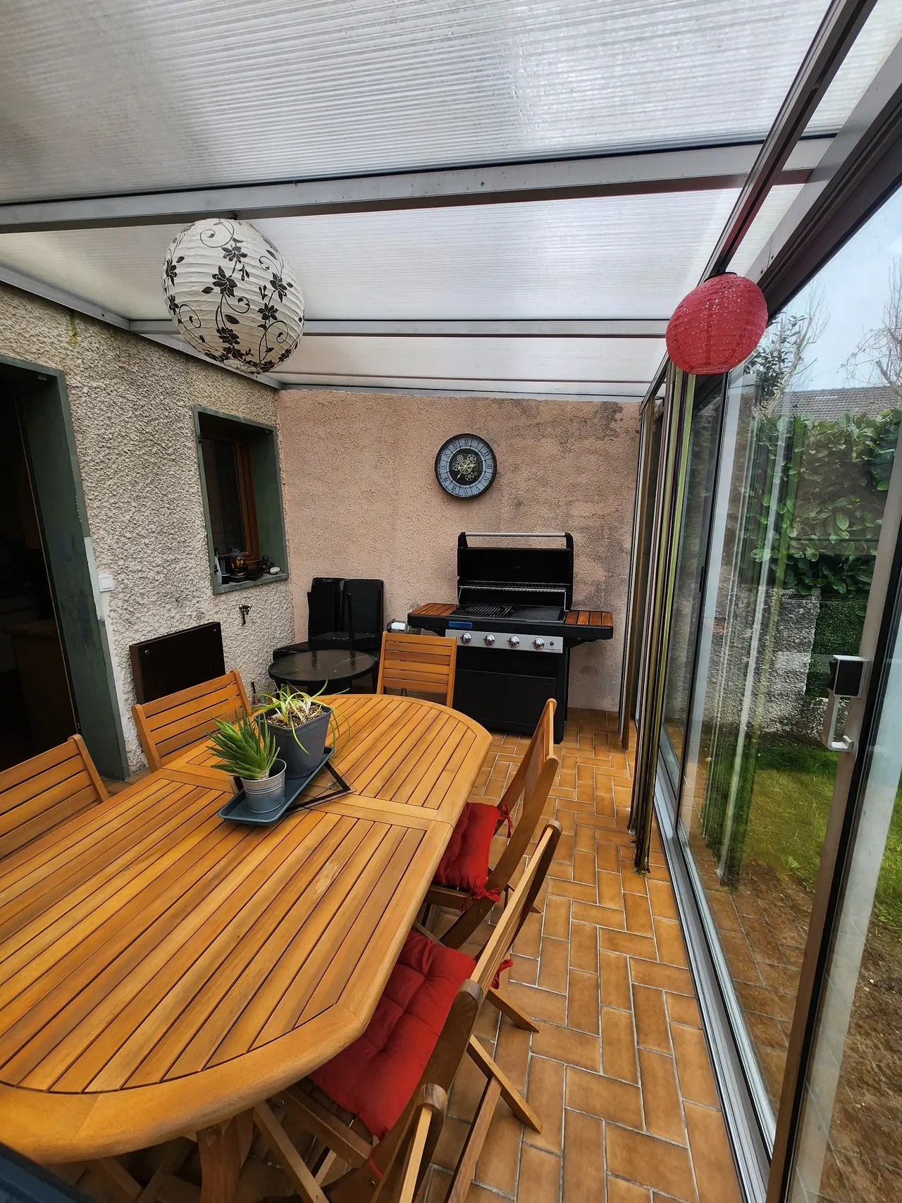 Une véranda meublée, fermée du côté de la maison par un mur.