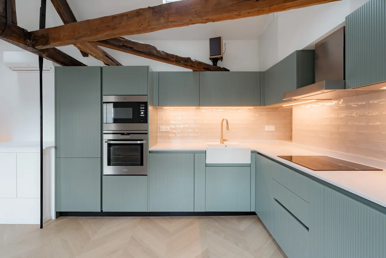 La cuisine éclairée sous les meubles hauts.