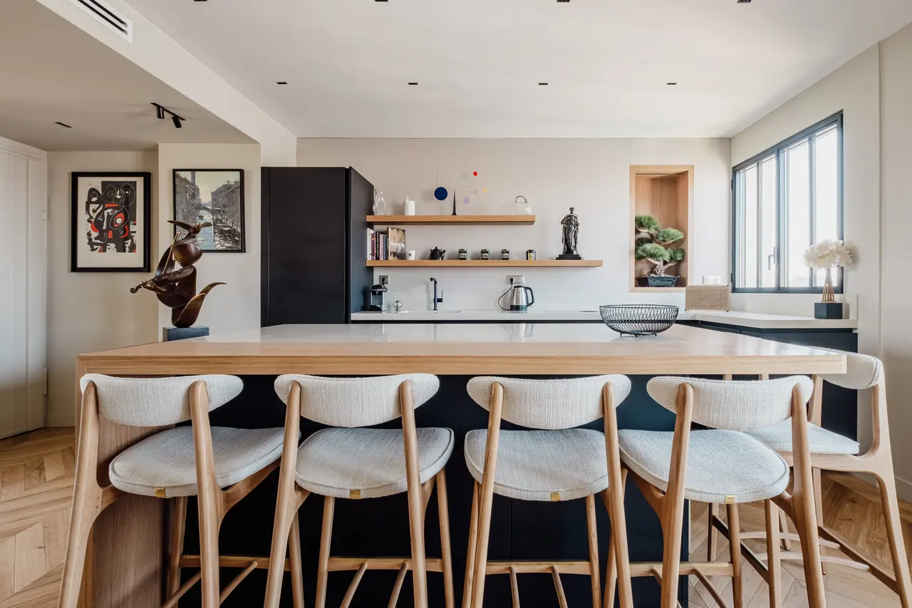 Cuisine de l'avenue de Suffren : îlot en chêne prolongé en table, façades noires.