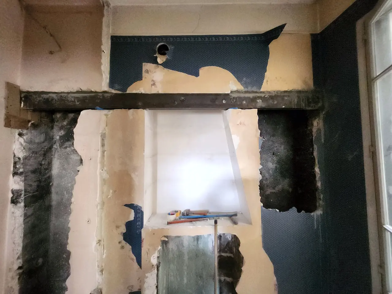 Poutre acier posée au-dessus d'un mur en cours d'ouverture.
